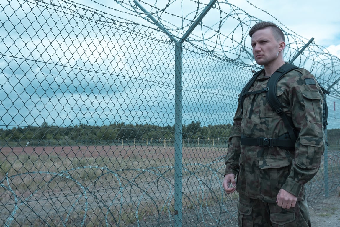 Soldier walking next to fence