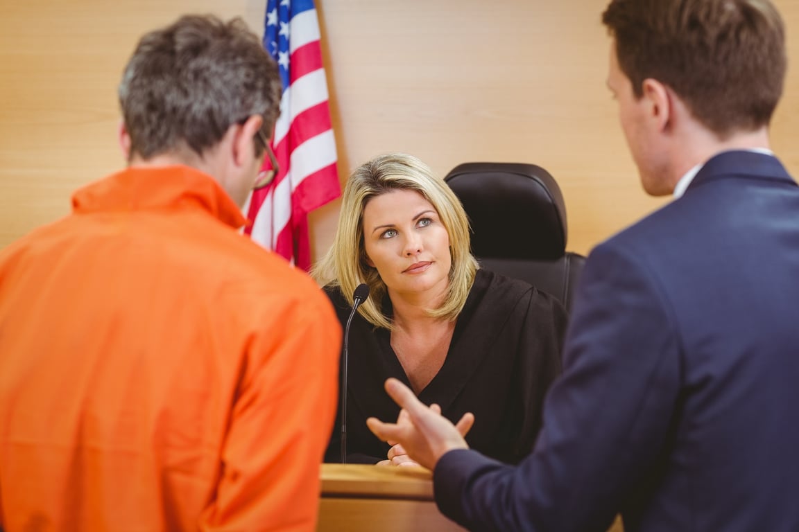 Judge and lawyer talking in front of a defendant